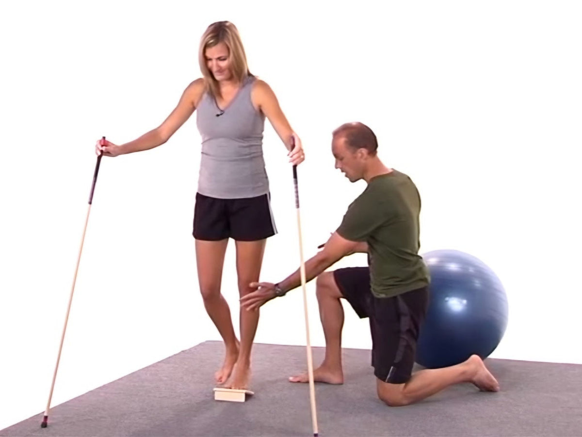 A coach guiding a runner through a Level 1 movement on the B2R board with the balance poles
